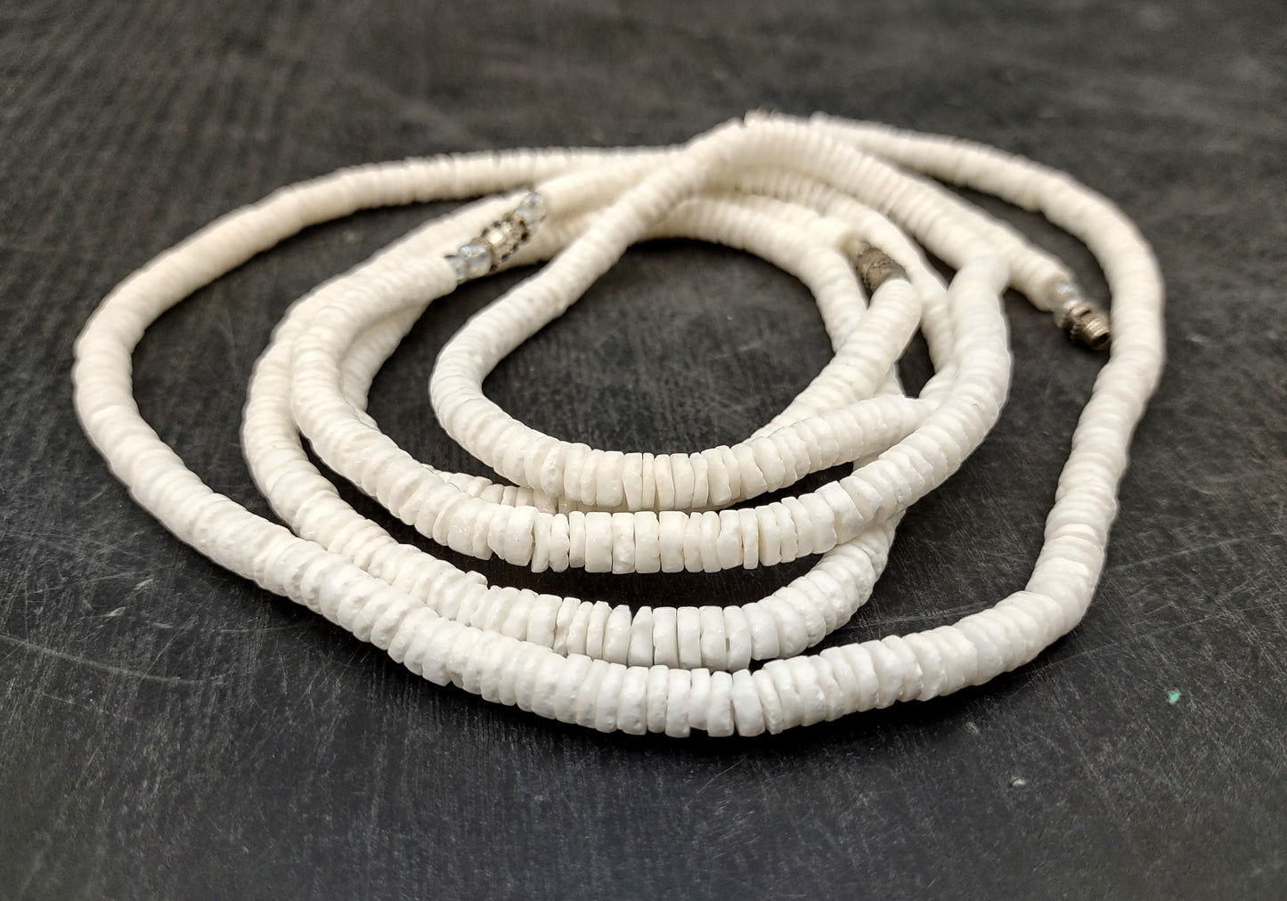 White Puka-Style Shell Necklace - (1 necklace 18 inches x 4-5mm) on blue background. Copyright 2022 SeaShellSupply.com.