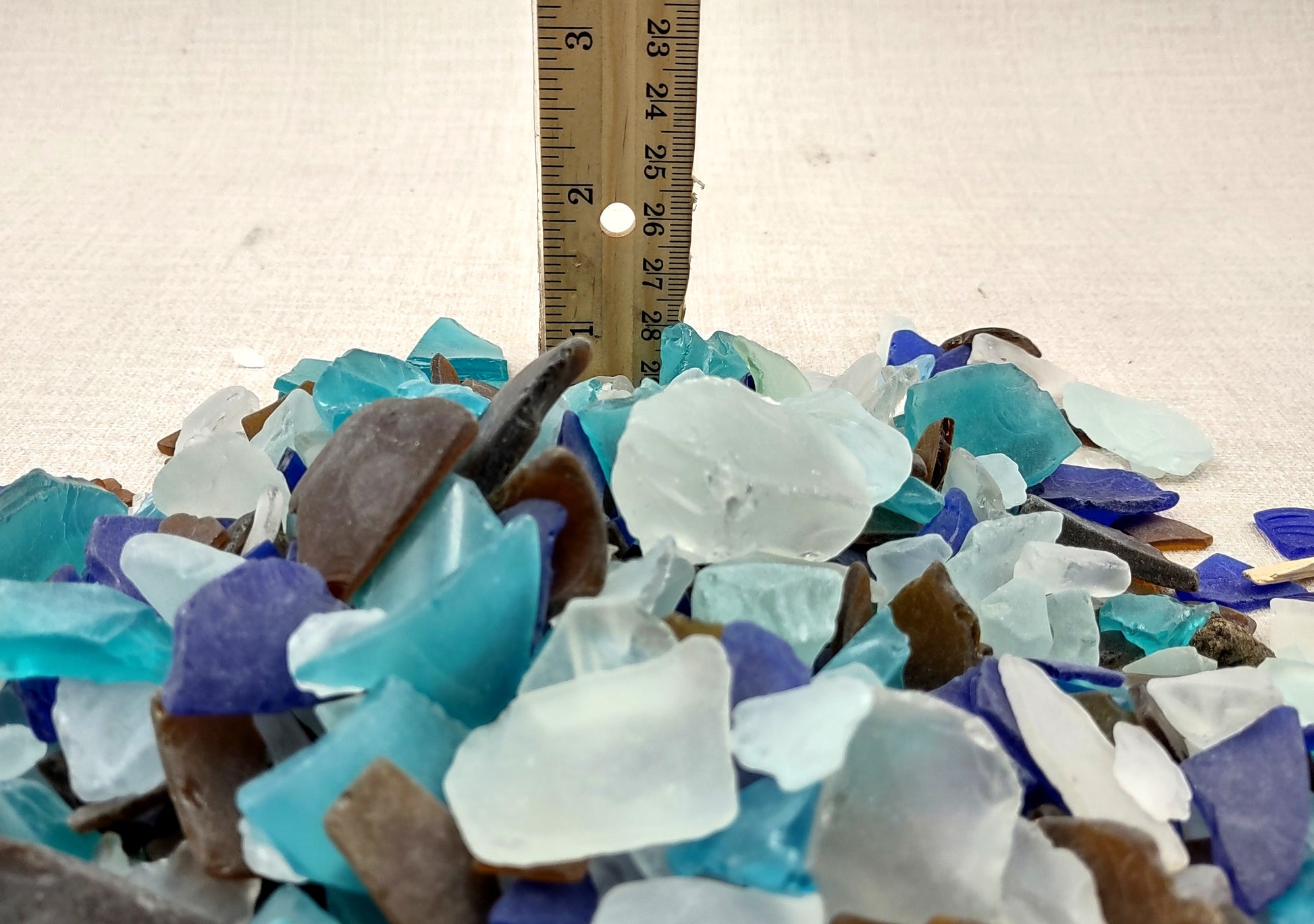 Beach Glass - Medium Tumbled Rough Brown, White & Blue Pacific Assorted - (approx. 1 Kilogram/2.2 lbs. .5-1.25 inches). Multiple blue, white, and brown fragments in a pile. All different shapes and sizes. Copyright 2024 SeaShellSupply.com.