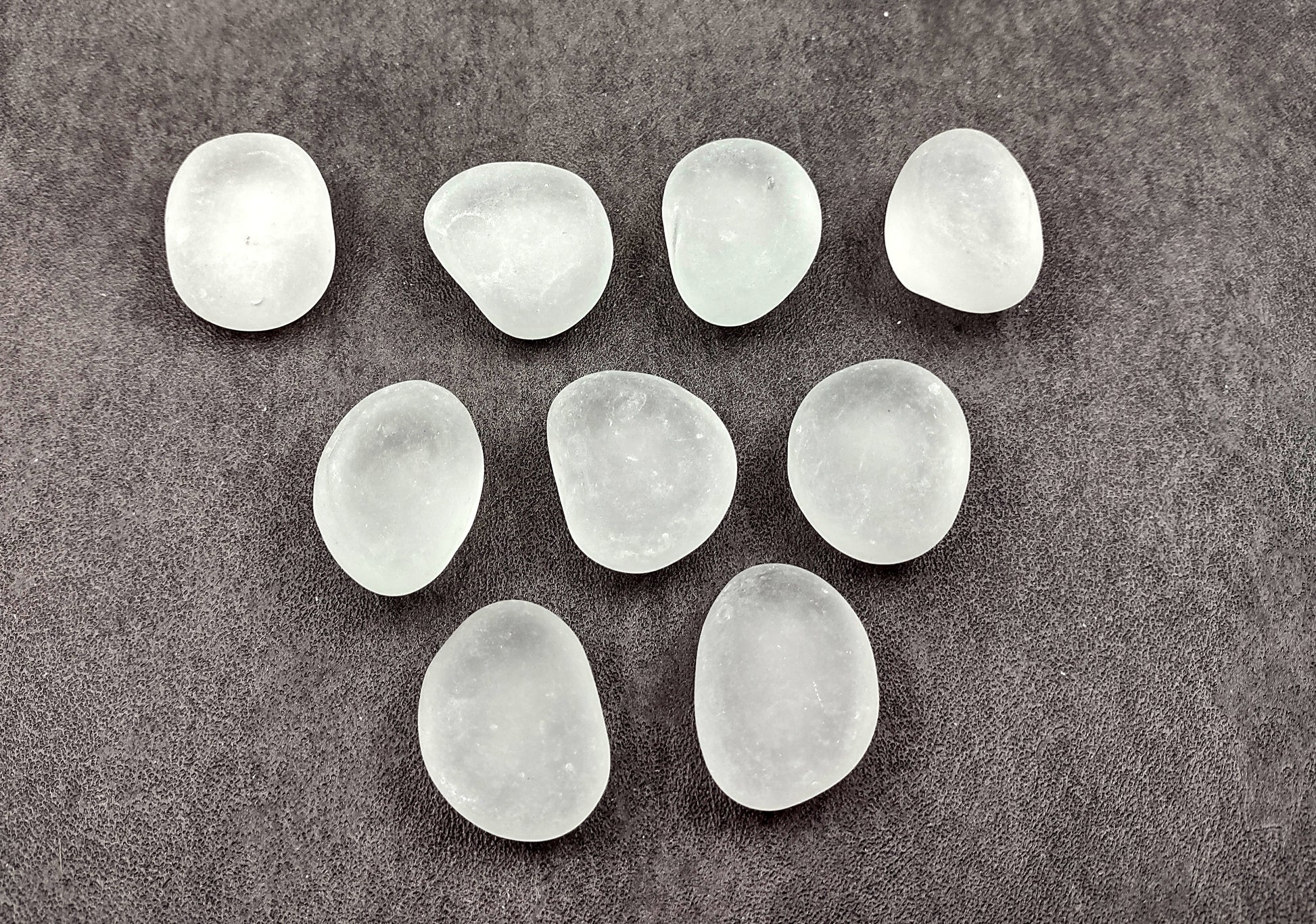 Beach Glass - Rounded Clear-White Frosted Pebbles - (approx. 1 Kilogram/2.2 lbs. 1-1.5 inches). Multiple lightly colored shells in a pile. Copyright 2024 SeaShellSupply.com.
