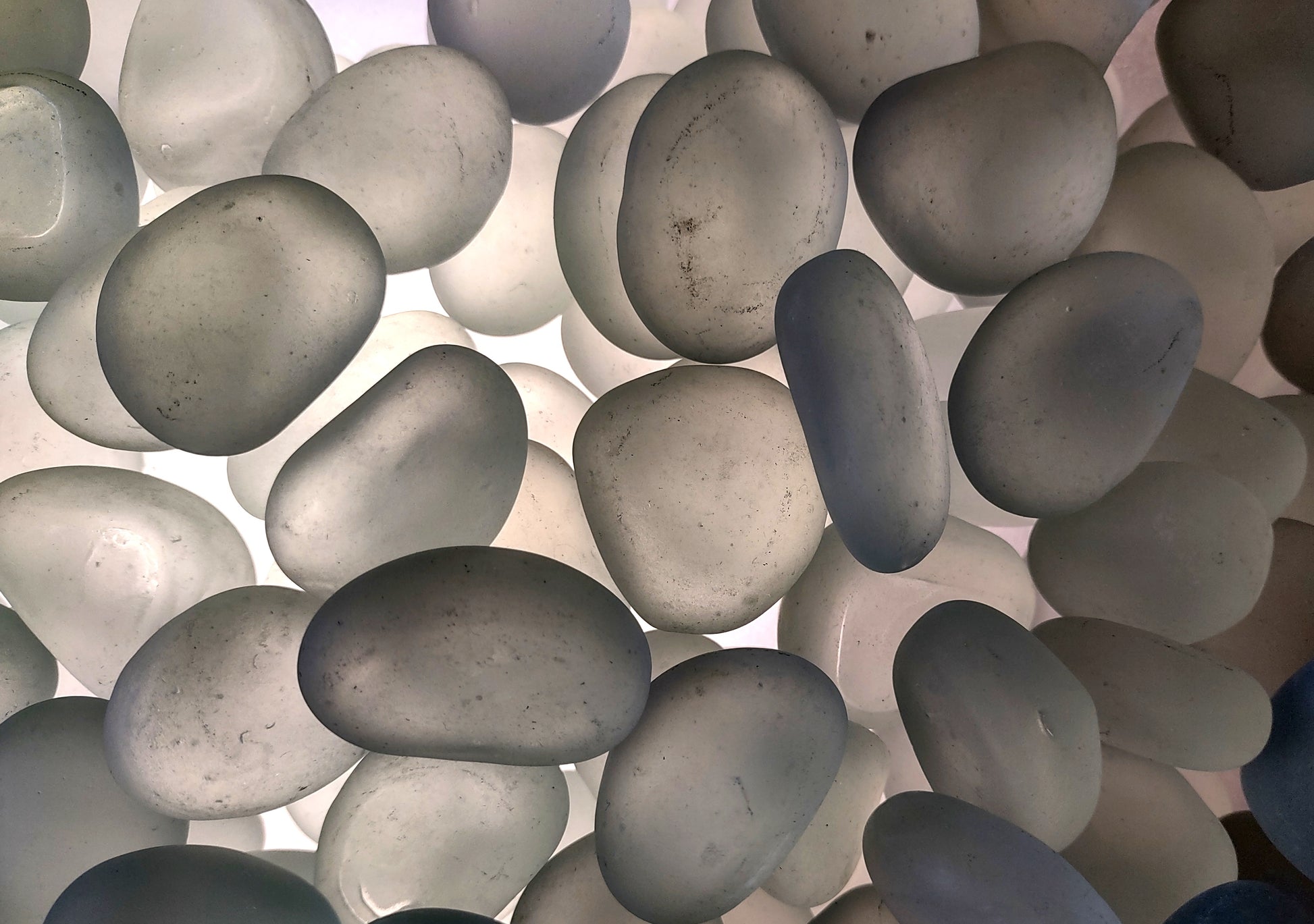 Beach Glass - Rounded Clear-White Frosted Pebbles - (approx. 1 Kilogram/2.2 lbs. 1-1.5 inches). Multiple lightly colored shells in a pile. Copyright 2024 SeaShellSupply.com.
