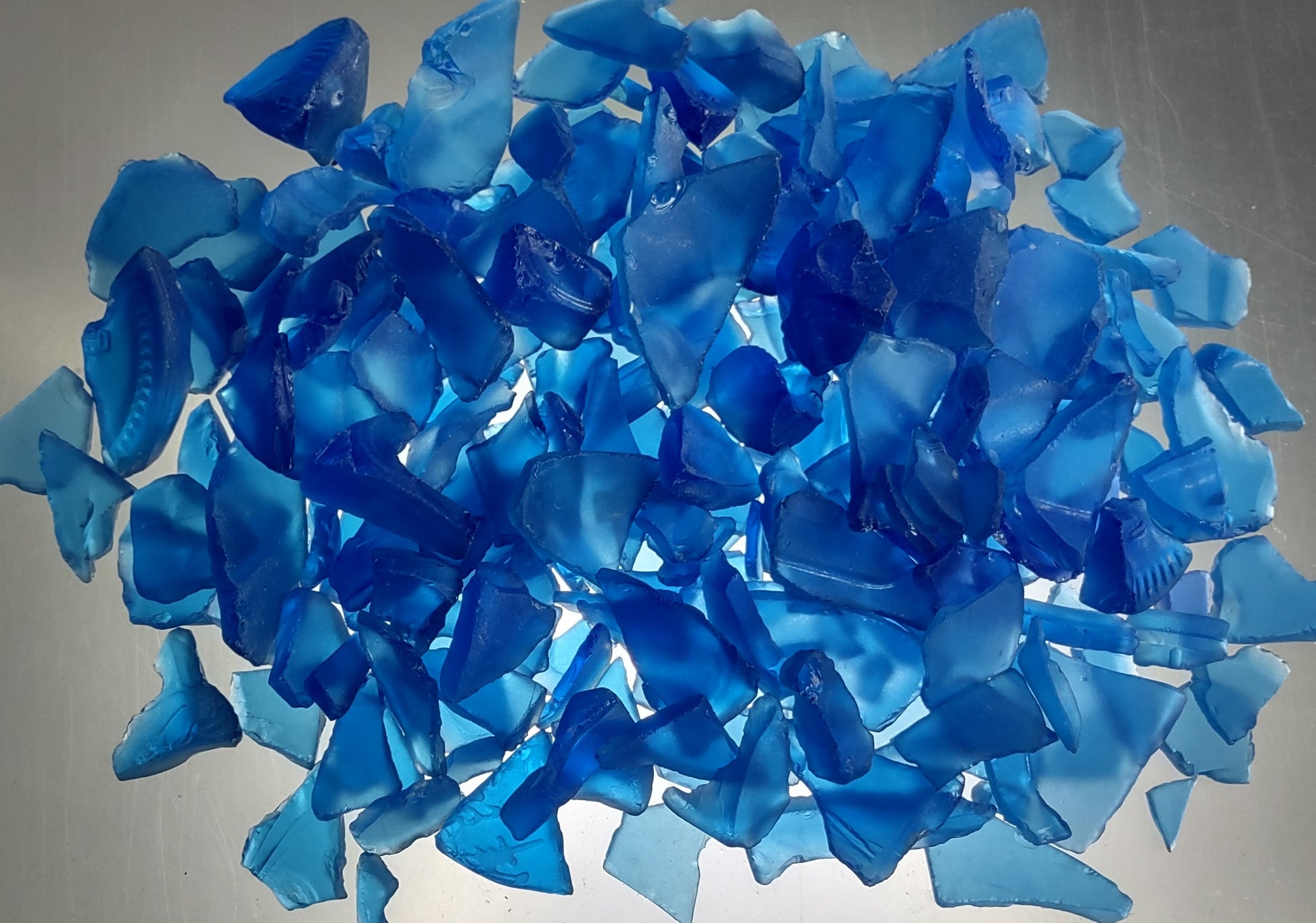Beach Glass - Medium Tumbled Rough Cobalt Blue - (approx. 1 Kilogram/2.2 lbs. .5-1.25 inches). Multiple shaded blue tiles in a pile, all are different sizes and shapes. Copyright 2024 SeaShellSupply.com.