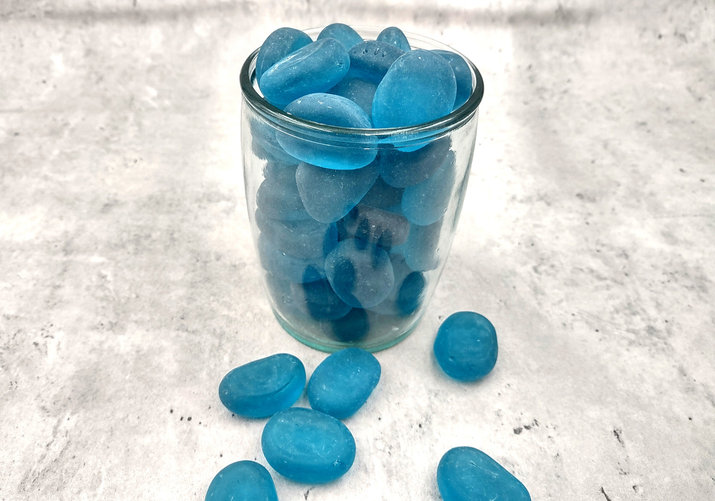 Beach Glass - Rounded Aqua Blue Pebbles - (approx. 1 Kilogram/2.2 lbs. 1-1.5 inches). Multiple smooth blue glass pebbles in a pile. Copyright 2024 SeaShellSupply.com.