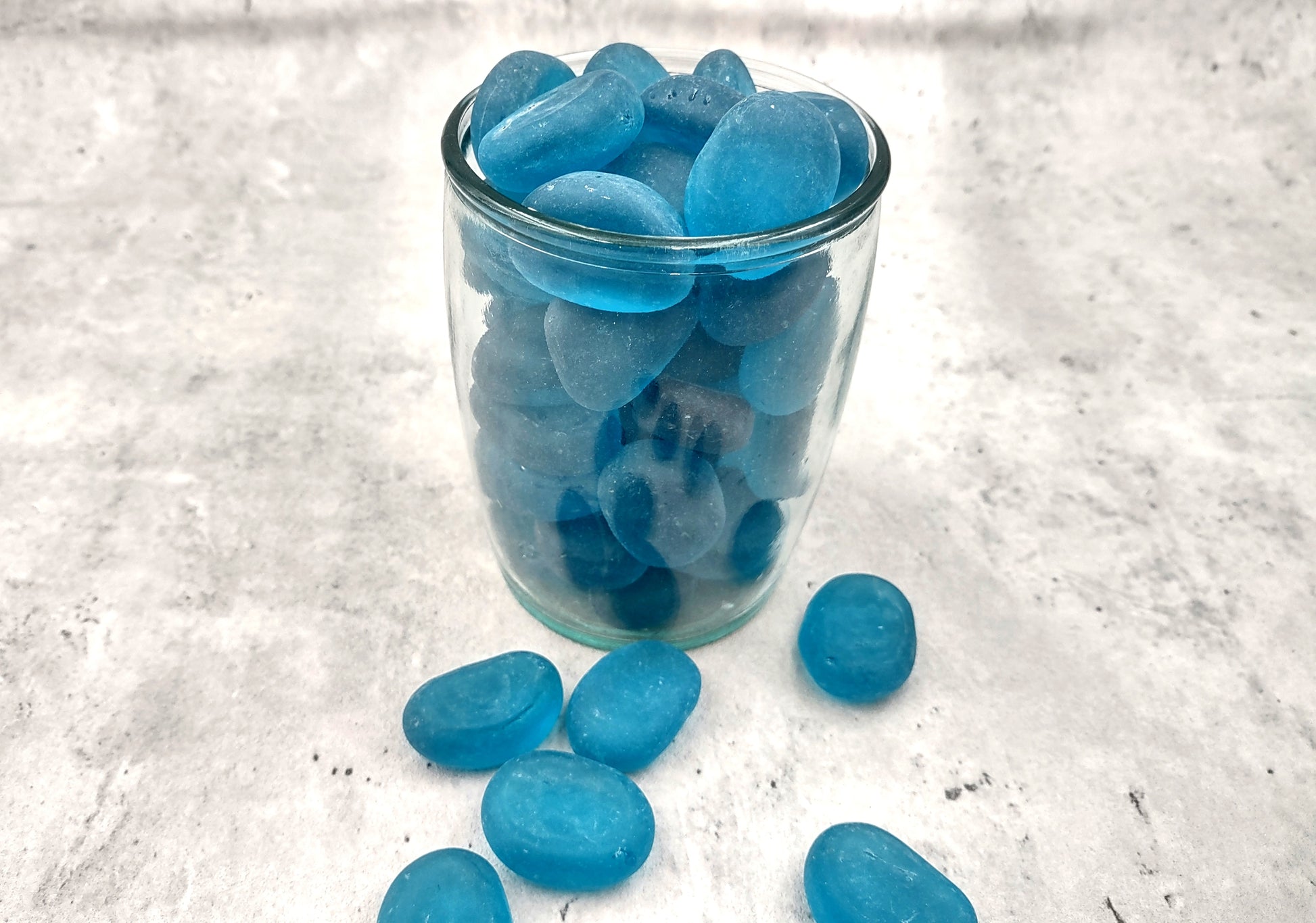 Beach Glass - Rounded Aqua Blue Pebbles - (approx. 1 Kilogram/2.2 lbs. 1-1.5 inches). Multiple smooth blue glass pebbles in a pile. Copyright 2024 SeaShellSupply.com.