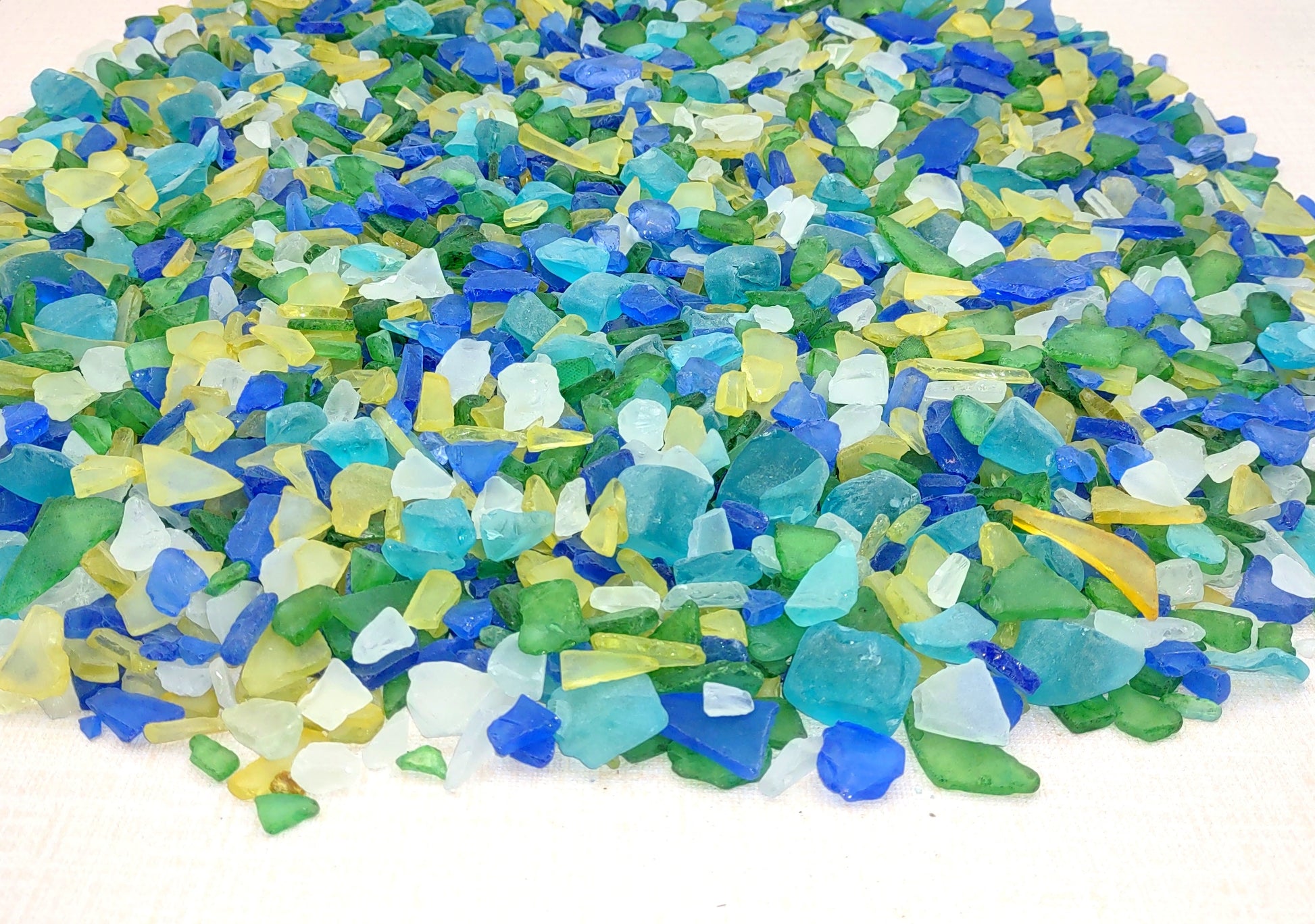 Beach Glass - Medium Tumbled Rough Blue, Green & White Atlantic Assorted - (approx. 1 Kilogram/2.2 lbs. .5-1.25 inches). Multiple different shapes and sizes pieces all in a pile. Copyright 2024 SeaShellMart.com.