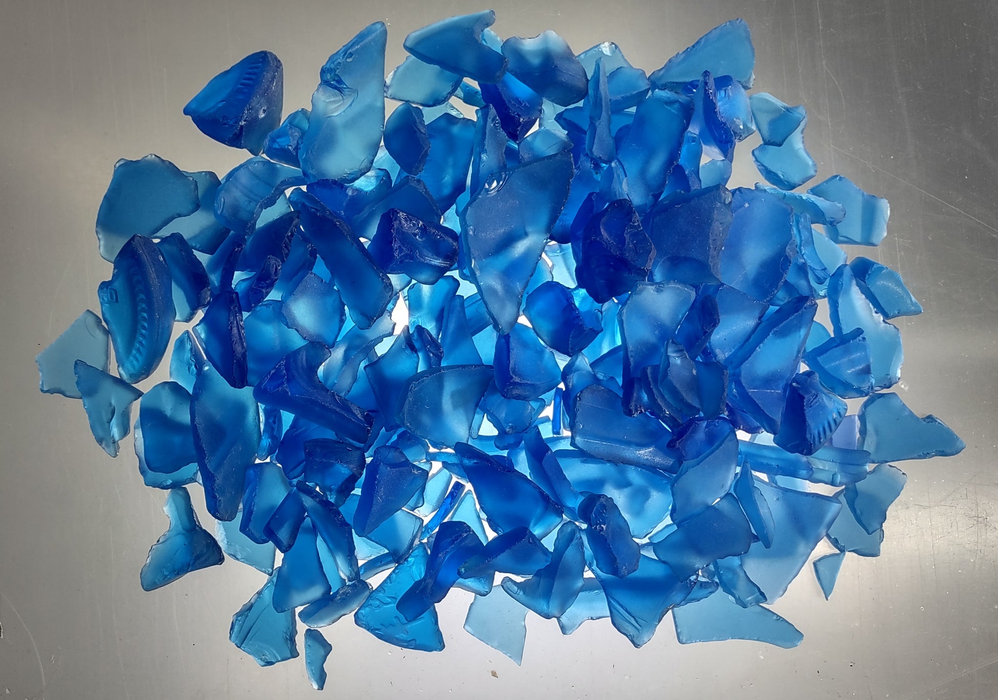 Beach Glass - Medium Tumbled Rough Cobalt Blue - (approx. 1 Kilogram/2.2 lbs. .5-1.25 inches). Multiple shaded blue tiles in a pile, all are different sizes and shapes. Copyright 2024 SeaShellSupply.com.
