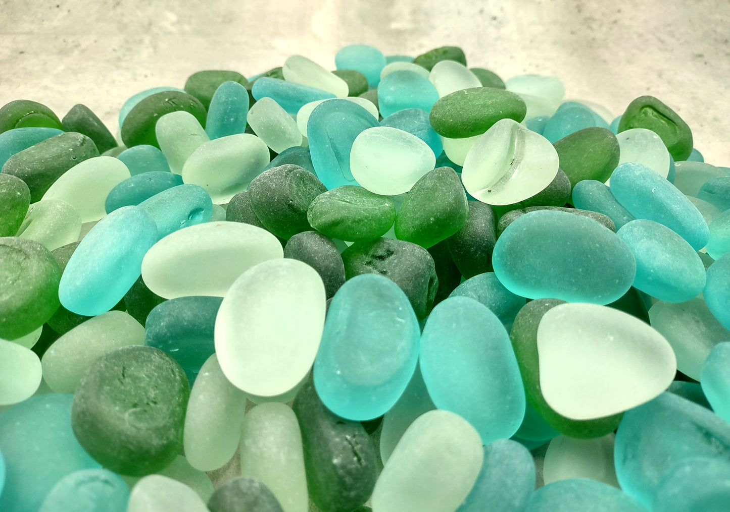 Beach Glass - Rounded Blue, Green & White Assorted Pebbles - (approx. 1 Kilogram/2.2 lbs. 1-1.5 inches). Multiple colored pebbles in a pile. Copyright 2024 SeaShellSupply.com.