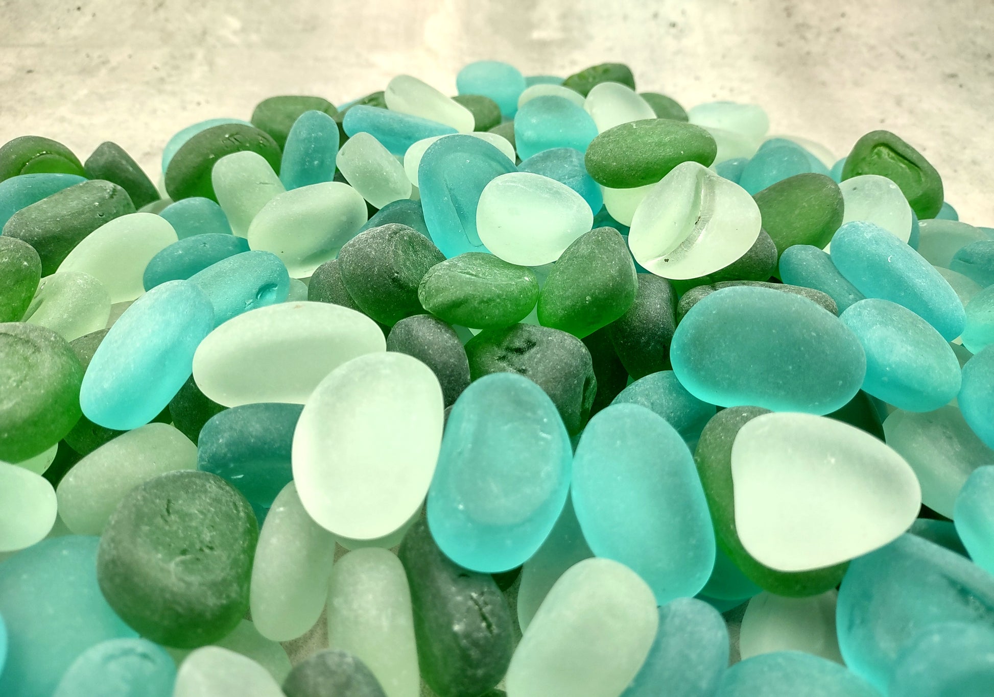Beach Glass - Rounded Blue, Green & White Assorted Pebbles - (approx. 1 Kilogram/2.2 lbs. 1-1.5 inches). Multiple colored pebbles in a pile. Copyright 2024 SeaShellSupply.com.