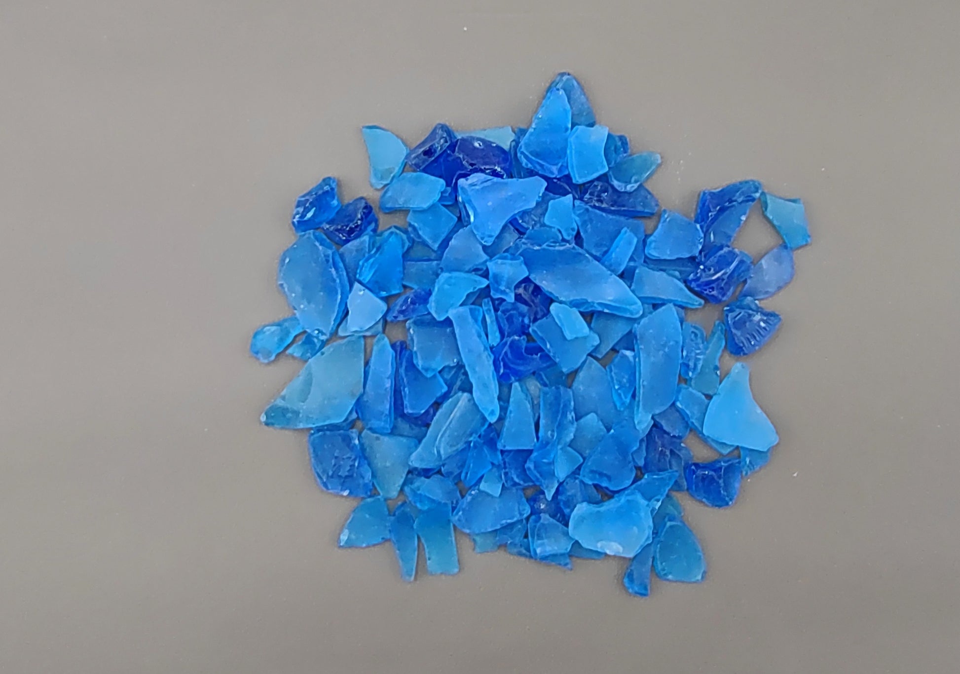 Beach Glass - Medium Tumbled Rough Cobalt Blue - (approx. 1 Kilogram/2.2 lbs. .5-1.25 inches). Multiple shaded blue tiles in a pile, all are different sizes and shapes. Copyright 2024 SeaShellSupply.com.