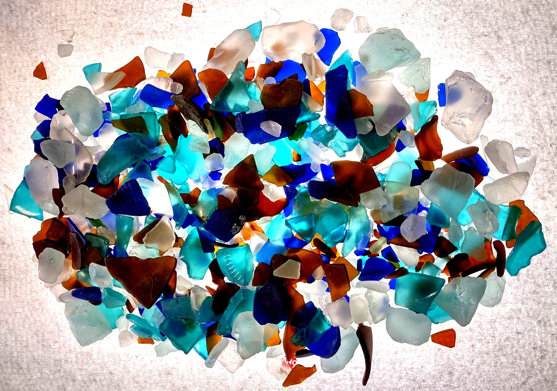 Beach Glass - Medium Tumbled Rough Brown, White & Blue Pacific Assorted - (approx. 1 Kilogram/2.2 lbs. .5-1.25 inches). Multiple blue, white, and brown fragments in a pile. All different shapes and sizes. Copyright 2024 SeaShellSupply.com.