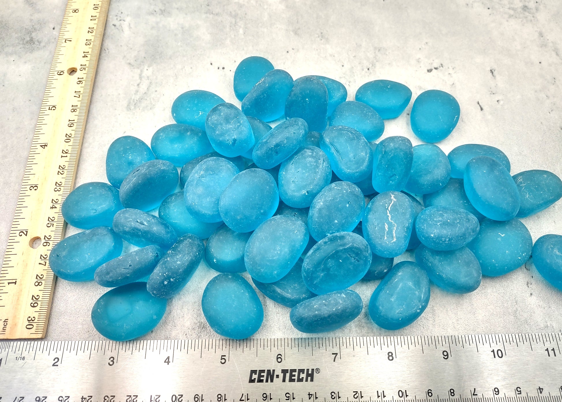 Beach Glass - Rounded Aqua Blue Pebbles - (approx. 1 Kilogram/2.2 lbs. 1-1.5 inches). Multiple smooth blue glass pebbles in a pile. Copyright 2024 SeaShellSupply.com.