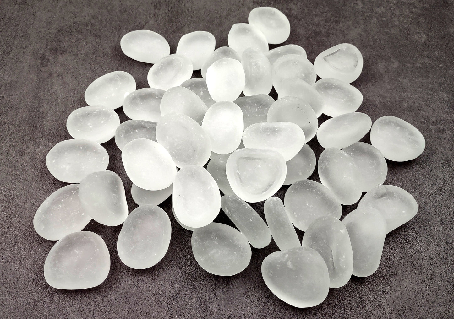 Beach Glass - Rounded Clear-White Frosted Pebbles - (approx. 1 Kilogram/2.2 lbs. 1-1.5 inches). Multiple lightly colored shells in a pile. Copyright 2024 SeaShellSupply.com.