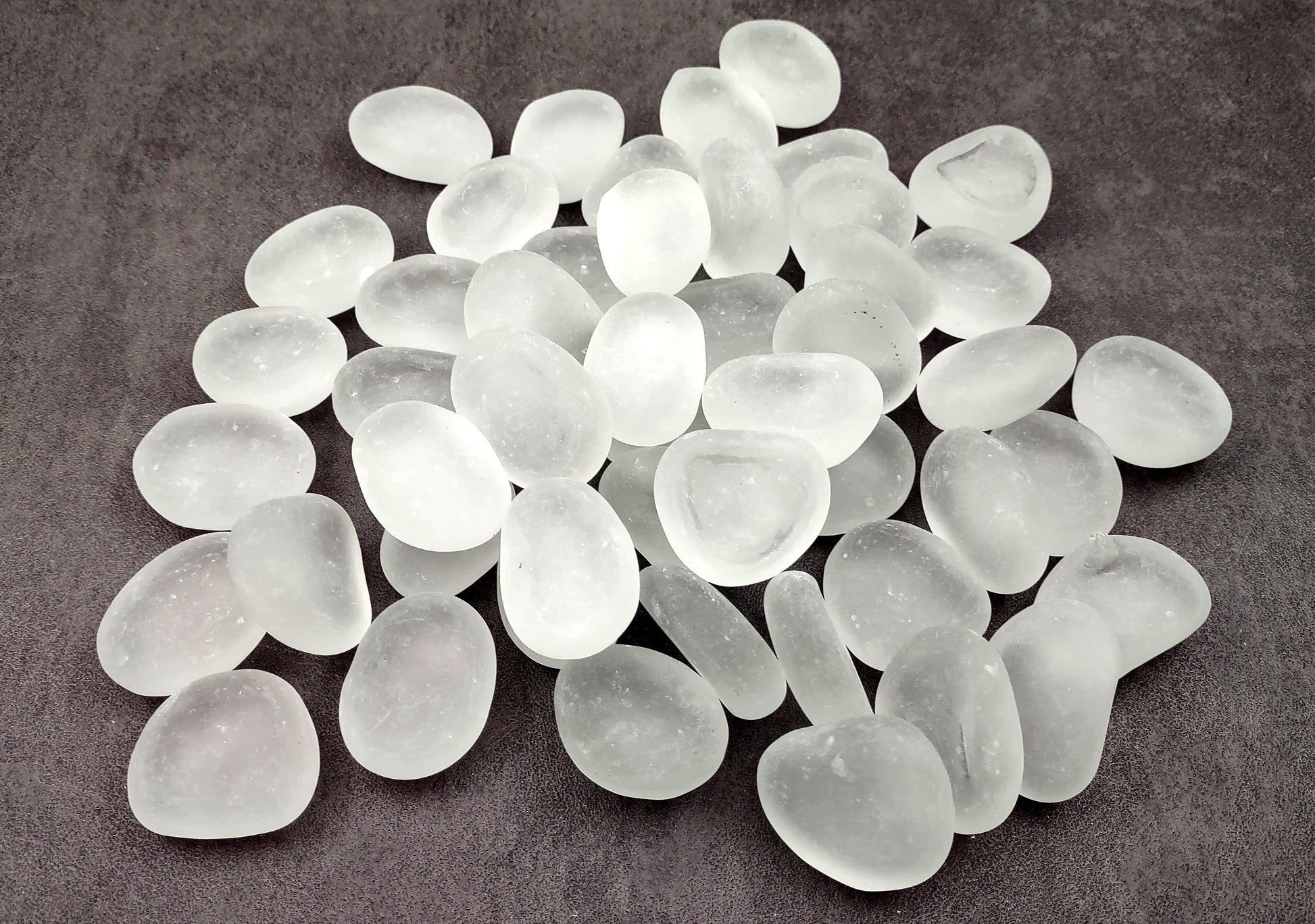 Beach Glass - Rounded Clear-White Frosted Pebbles - (approx. 1 Kilogram/2.2 lbs. 1-1.5 inches). Multiple lightly colored shells in a pile. Copyright 2024 SeaShellSupply.com.