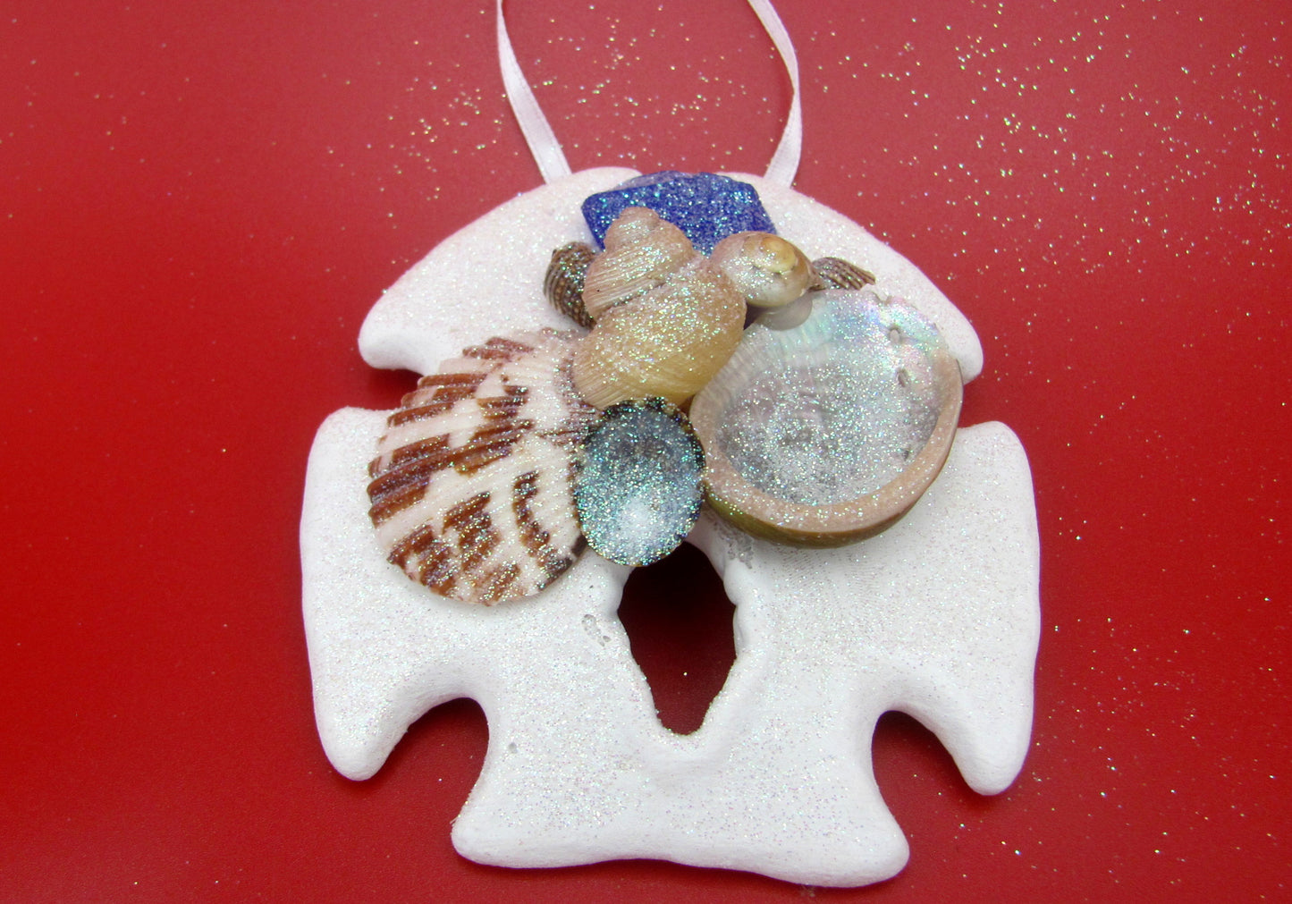 Frosted Blue Sea Glass Sand Dollar Ornament (1 sand dollar approx. 3-5 inches) on red background. Copyright 2022 SeaShellSupply.com.